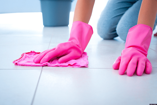 a person wearing pink gloves cleaning the floor with a pink cloth