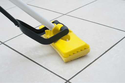 a yellow sponge mop on a white tile floor