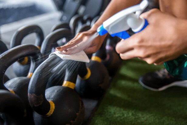 Close up image of a cleaning professional wiping off weights. Learn more about gym cleaning essentials with JAN-PRO Cleaning & Disinfecting in Central GA.