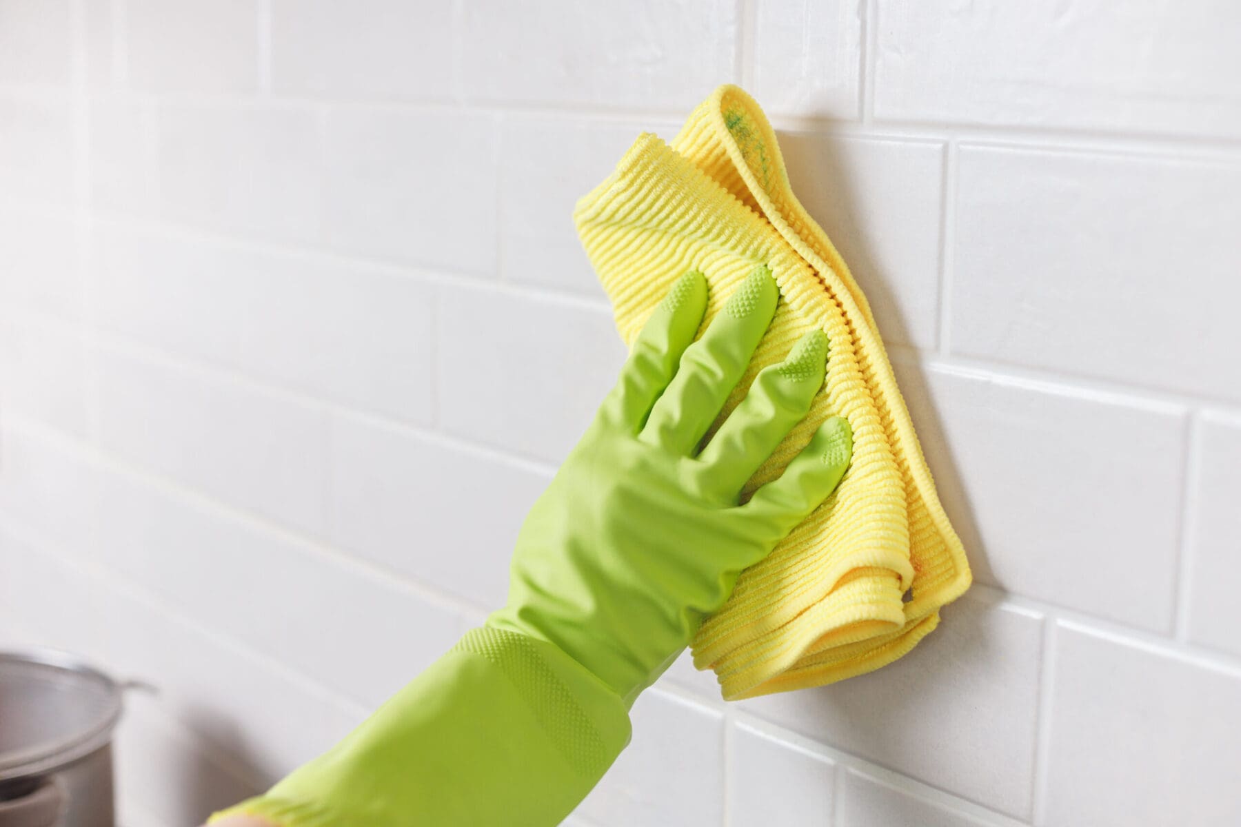 Hand in Gloves Washing White Tiled Wall in Kitchen with Yellow Microfiber and Spray Bottle with Detergent Your Step-by-Step Guide to Deep Cleaning Grout
