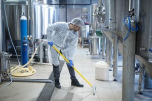 Professional industrial cleaner in protective uniform cleaning floor of food processing plant. Industrial Cleaning Tips for Safer Atlanta Facilities