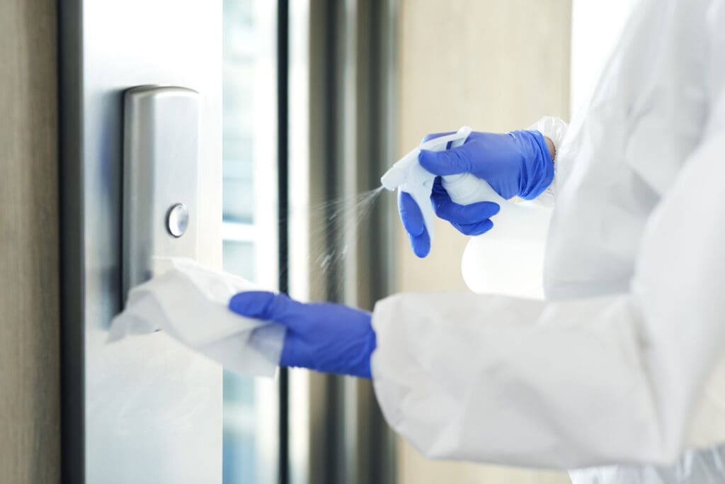 person disinfecting an elevator panel