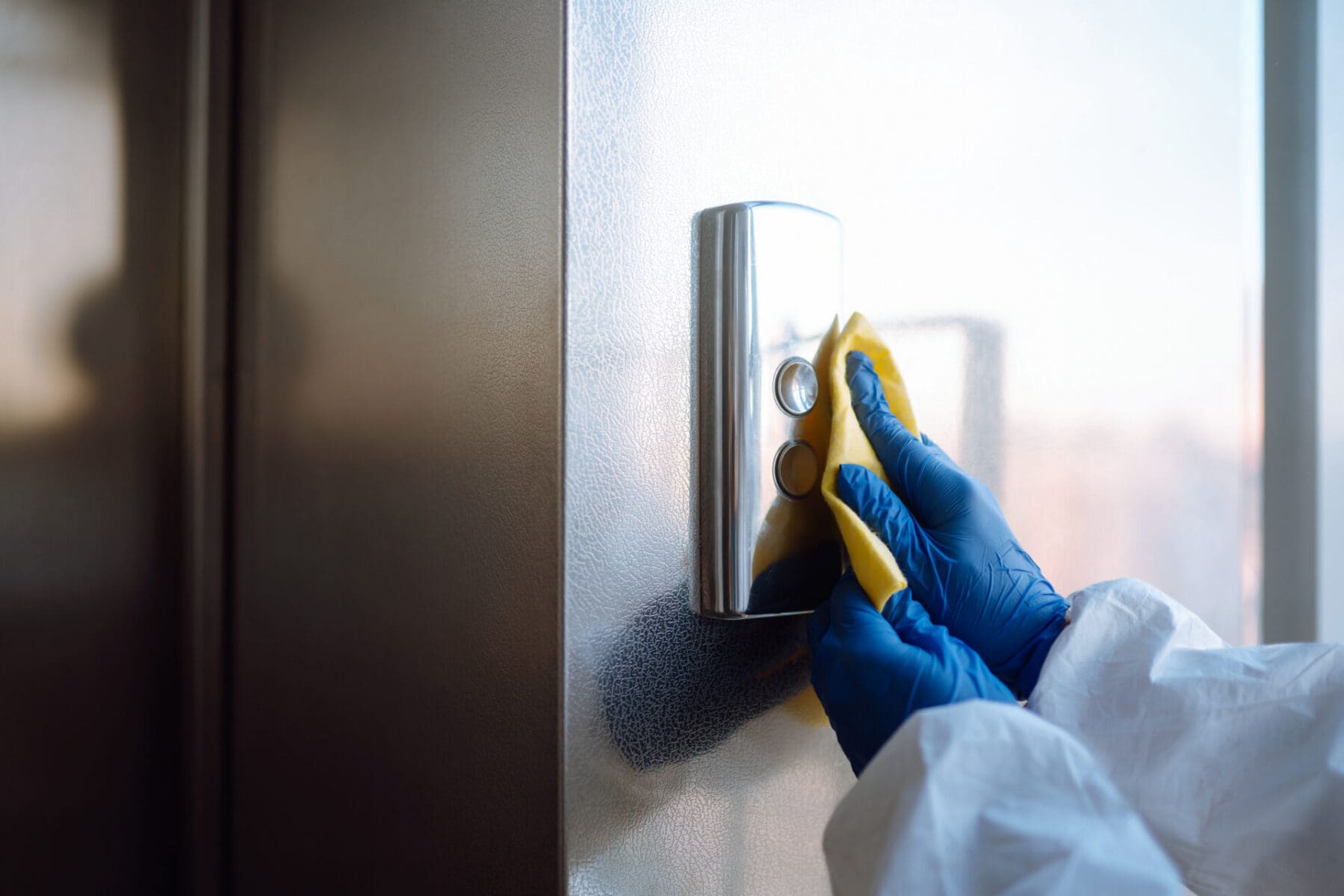 sanitizing-elevator-button-with-gloves-and-cloth